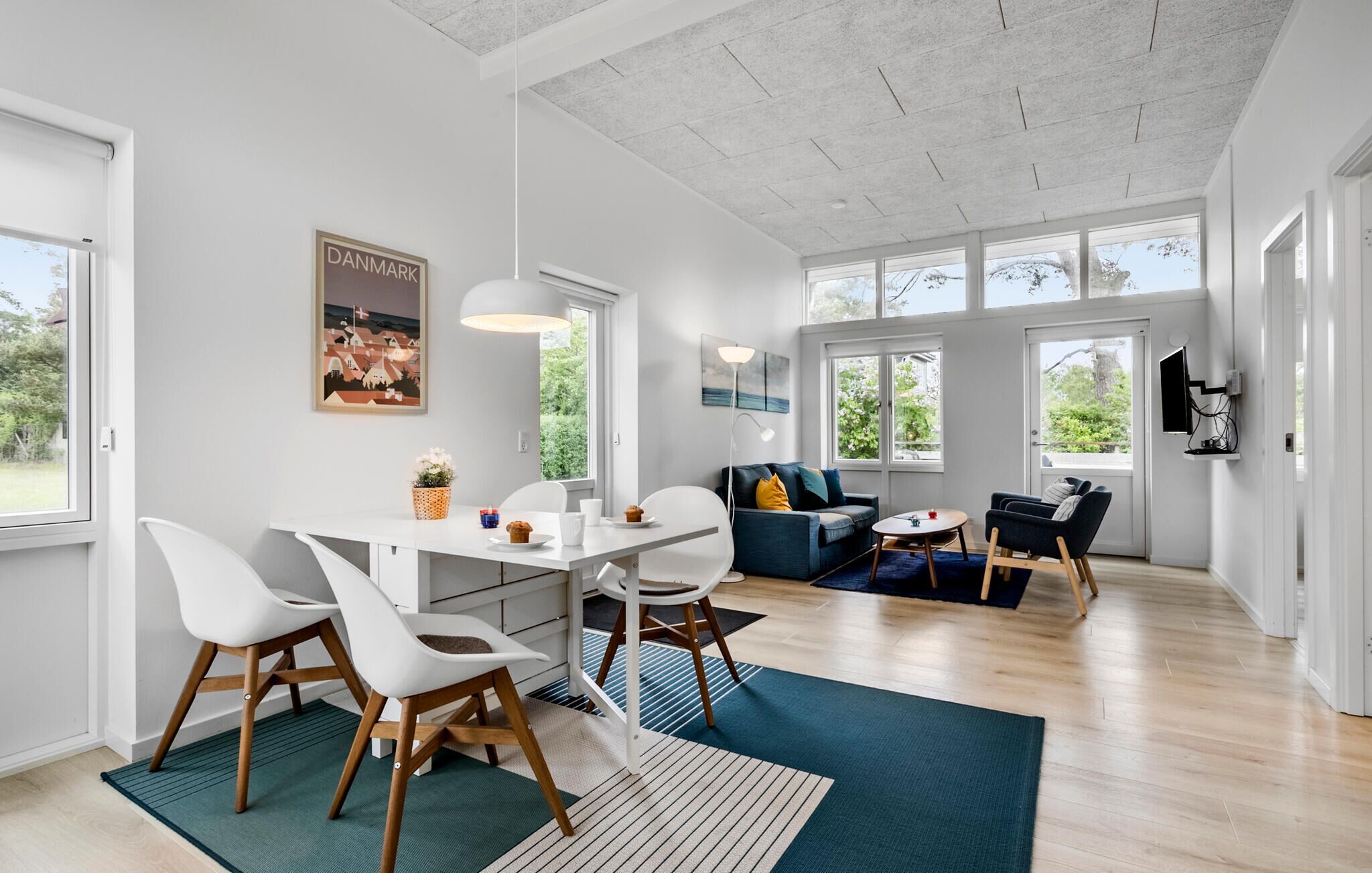 Un salon moderne avec un coin repas, de grandes fenêtres et des œuvres d’art accrochées aux murs.