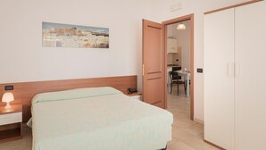 A bedroom with a bed, bedside table, lamp, and a painting on the wall. - Nice apartment in Villasimius with WiFi (Villasimius)