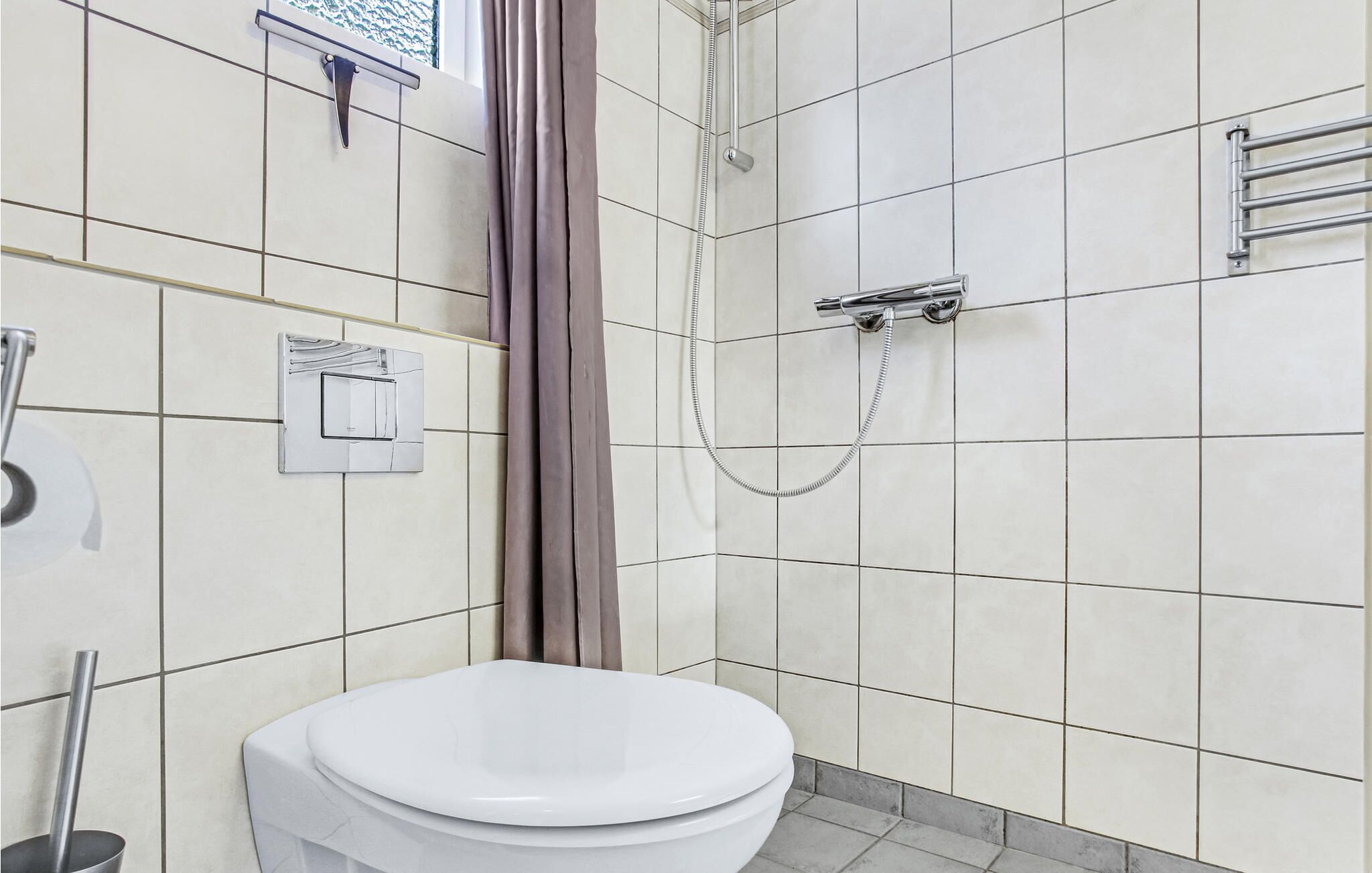 A bathroom with a toilet, a shower, and a towel rack.