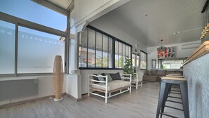 Un salon moderne comprenant un canapé, une table basse et un coin bar avec des tabourets.