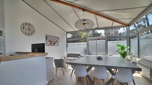 Une salle de réunion moderne avec une longue table, des chaises blanches, une horloge et une plante.