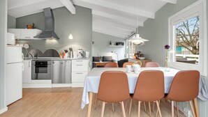 A modern kitchen with white cabinetry, stainless steel appliances, and a dining area with a white table and brown chairs.