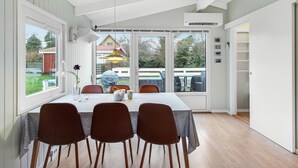 A dining area with a table set for four, large windows, and a view of the backyard.