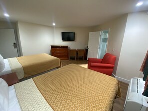 A hotel room with two beds, a desk, a chair, a television, and an air conditioning unit. - Royale Inn Motel (Whittier)