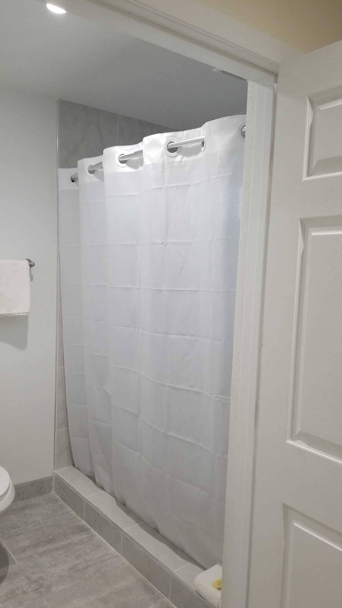 Un baño con cortina de ducha, un inodoro y un perchero para toallas.