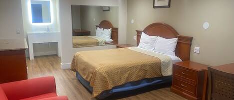 A hotel room with a bed, a desk, a chair, a mirror, and a window.