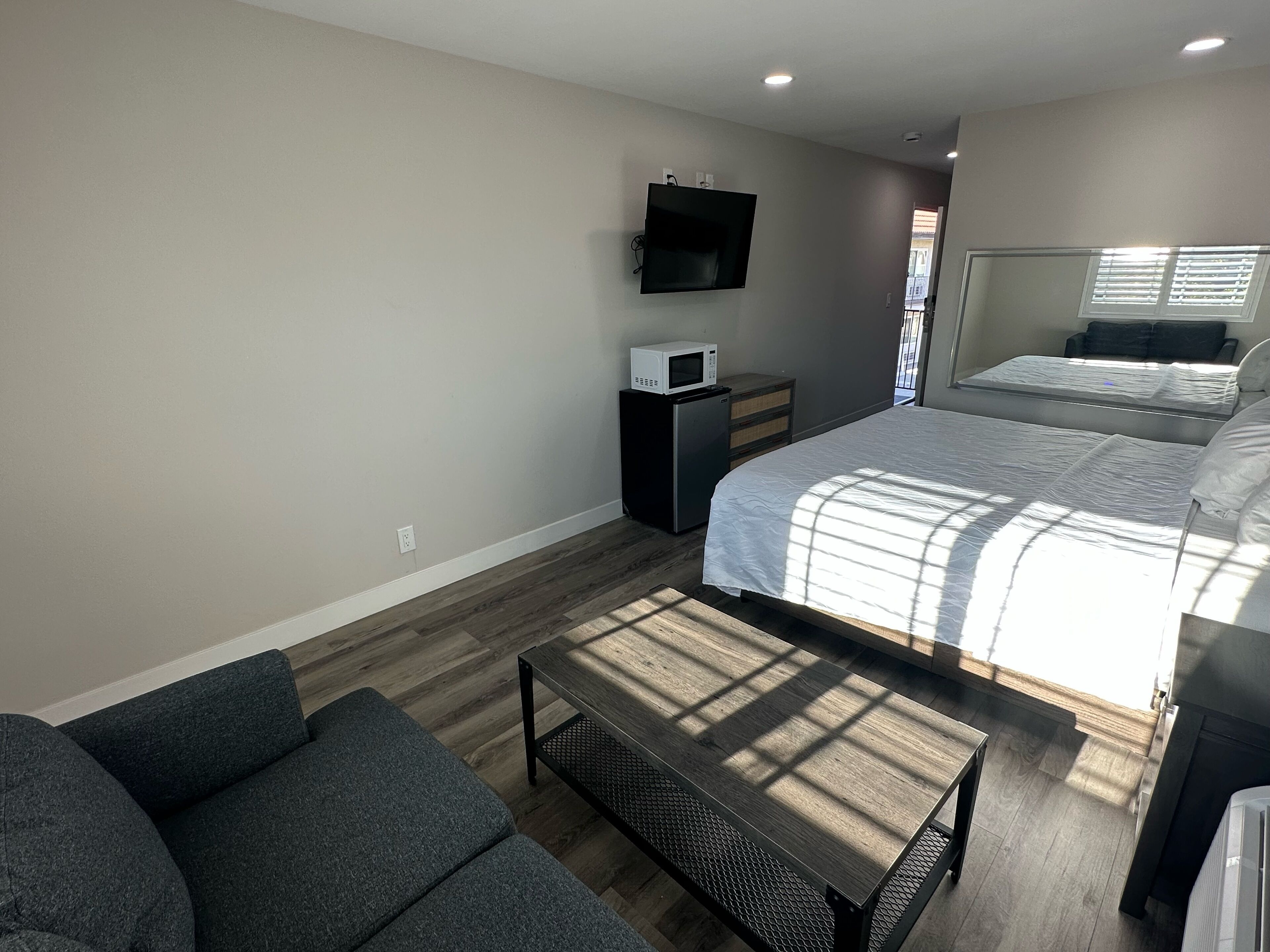 A bedroom with a bed, a TV, a microwave, and a small desk.