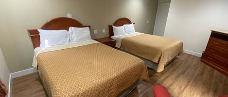 Une chambre d’hôtel avec deux lits, des têtes de lit en bois et une chaise rouge.