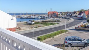 Uma marina costeira com barcos atracados, uma estrada serpenteando pela área e edifícios residenciais ao fundo.