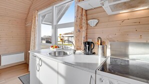 Una cocina compacta con un lavamanos, una cafetera y una estufa.
