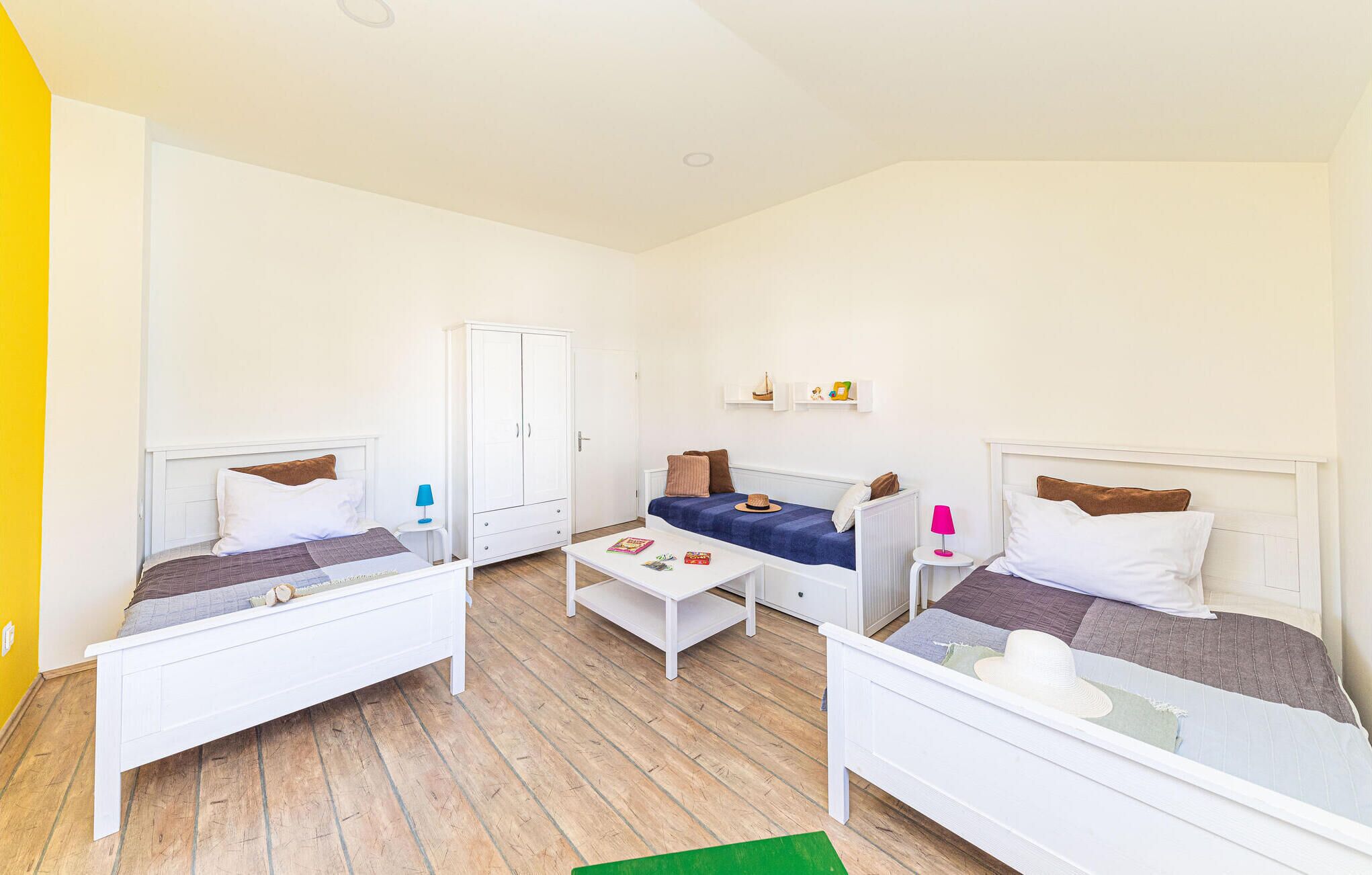 Una habitación con dos camas individuales, un sofá, una mesita y un armario.