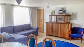 Ein Wohnzimmer mit einer Couch, einem Esstisch, Stühlen, einem Schrank und einer Tür.