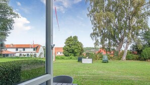 A view from a window with a table and chairs, a grassy yard, and houses in the background. - Awesome apartment in Allinge with WiFi (Allinge)