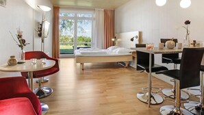 A modern hotel room with a bed, a dining area with a table and chairs, and a view through the glass door. - Awesome apartment in Allinge with WiFi (Allinge)