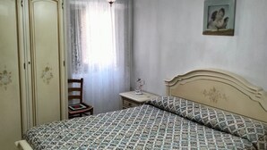 Ein Schlafzimmer mit Bett, Nachttisch, Stuhl, Kleiderschrank und einem Bild an der Wand.