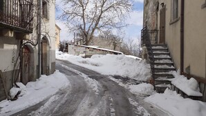 Eine enge Straße mit schneebedecktem Boden und Stufen, die zu einem Gebäude führen.
