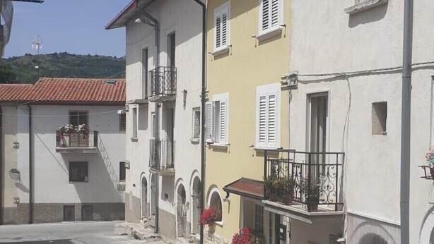 Eine enge Straße mit Häusern, die Balkone und kleine Fenster haben.