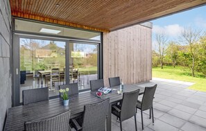 Un espace de restauration en plein air au design moderne, avec une table en bois foncé et des chaises en osier.