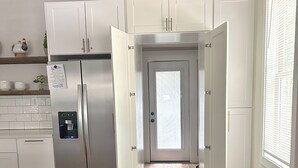 A modern kitchen with white cabinets, a stainless steel refrigerator, and a wooden floor.