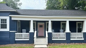 A two-story house with a front porch, a pink door, and a mailbox.
