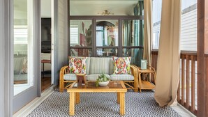 A porch with wicker furniture, a patterned floor, and a view of the street.