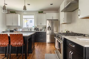 A modern kitchen with white cabinets, stainless steel appliances, and a central island with seating.