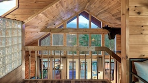 Interno in legno con soffitto alto, ampie finestre e vista sull'esterno.