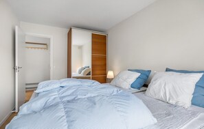 Een hotelkamer met een bed, nachtkastje, lamp en een kledingkast.