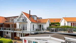 A modern building with a flat roof, a balcony, and a sign reading "GUDHJEM CAMPING". - Amazing apartment in Gudhjem with WiFi (Gudhjem)