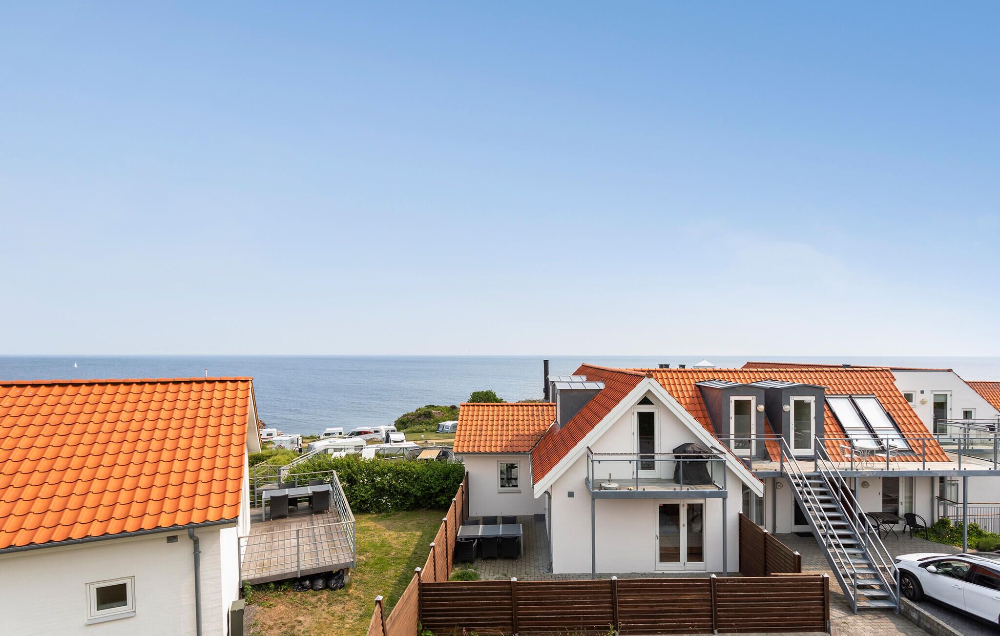 Un área residencial costera con casas de techo rojo y vista al mar.