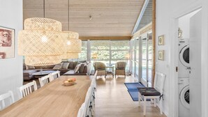 Une cuisine spacieuse avec un plancher en bois, une table à manger avec des chaises, une grande fenêtre et un lave-linge encastré.