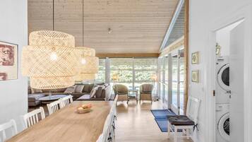 Une cuisine spacieuse avec un plancher en bois, une table à manger avec des chaises, une grande fenêtre et un lave-linge encastré.