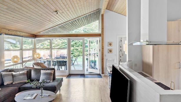 Un salon spacieux avec un plafond en bois, une grande fenêtre et un coin cuisine moderne.