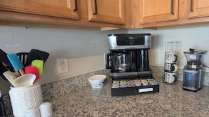 Eine Küche mit Kaffeemaschine, Kaffeemühle, Wasserkocher und Geschirr.