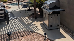 Eine Außenpatio mit Grill, überdachter Sitzgruppe und Pool.