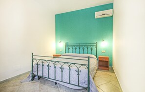 A single bed with a metal frame and a headboard, a nightstand with a lamp, and a wall-mounted air conditioner. - Gorgeous apartment in San vito lo Capo with swimming pool (San vito lo Capo)