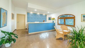 A reception area with a blue counter, wicker chairs, and a large window with a view. - Cozy apartment in Badesi (Badesi)