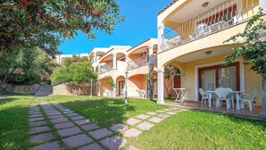 A courtyard with a stone pathway leading to a building with multiple balconies and outdoor seating. - Cozy apartment in Badesi (Badesi)