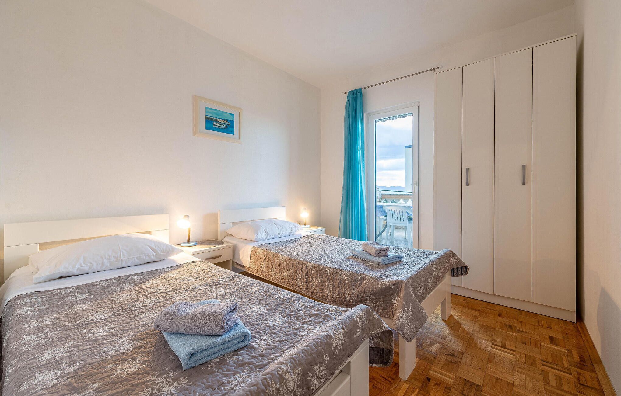 Ein Hotelzimmer mit zwei Betten, einem Balkon mit Aussicht und einem Kleiderschrank.