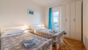 Ein Hotelzimmer mit zwei Betten, einem Balkon mit Aussicht und einem Kleiderschrank.