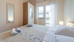 Ein Hotelzimmer mit Bett, einem großen Spiegel, einem Fenster mit Vorhängen und Blick nach draußen.
