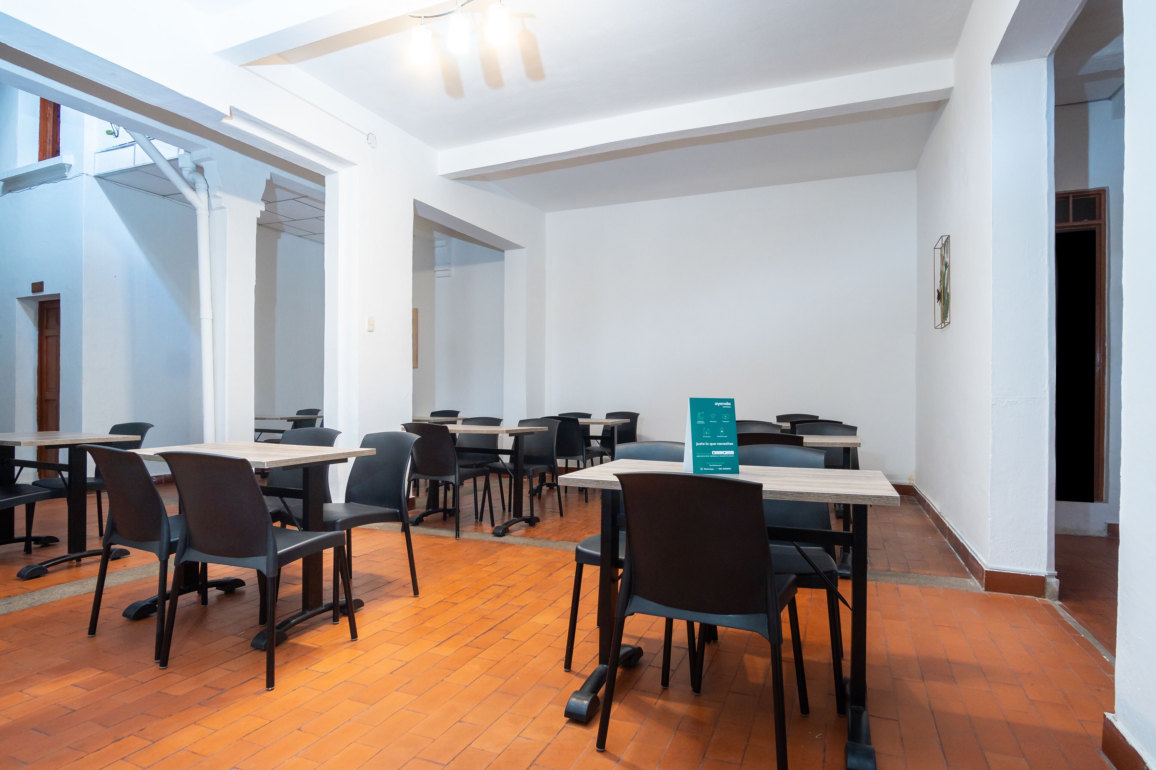 A conference room with tables and chairs, white walls, and a wooden floor.