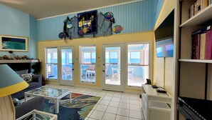 A room with a view of the ocean, a bookshelf, a table with a glass top, and a patterned rug. - Great price!Beachfront with Stunning gulf view from this Great home with hot tub (Saint George Island)