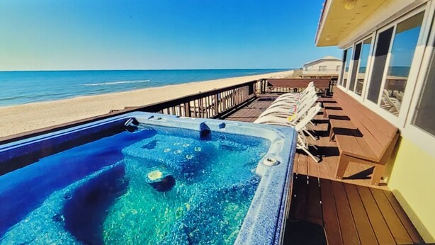 A deck with a hot tub, lounge chairs, and a view of the ocean. - Great price!Beachfront with Stunning gulf view from this Great home with hot tub (Saint George Island)