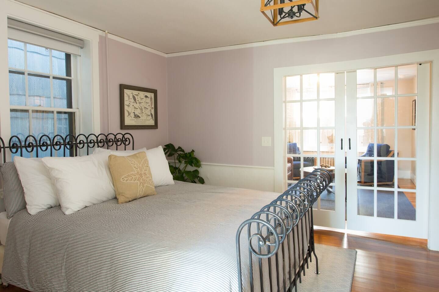A bedroom with a bed, a window, a door, and a plant.