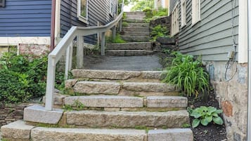 A set of stone steps leading up to a house with a white railing.