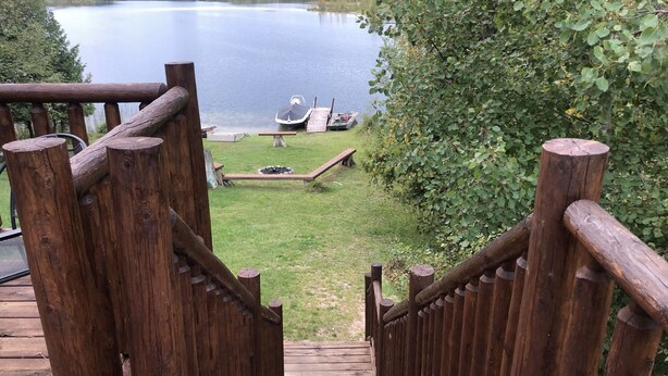Un escalier en bois mène à une zone de quai où se trouvent des bateaux et une pelouse verdoyante.