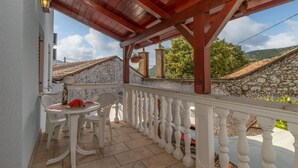 A balcony with a wooden pergola, white balustrade, and a table with chairs. - Beautiful home in Tribalj with sauna (Tribalj)