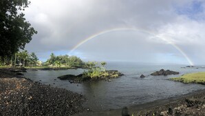 Un paysage côtier avec un arc-en-ciel, une côte rocheuse et une végétation luxuriante.