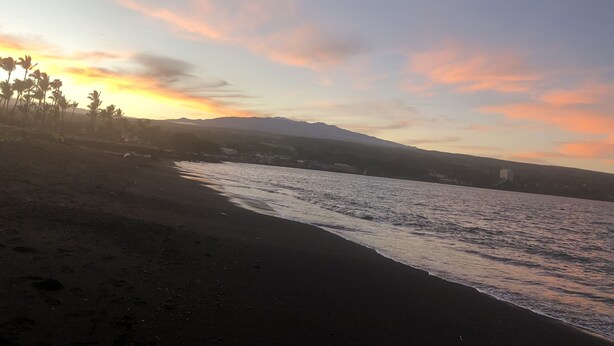 Une plage avec vue sur les montagnes et un coucher de soleil.